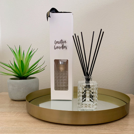 Diamond Reed Diffusers, one in it's box, the other open, atop a gold platter on a table.