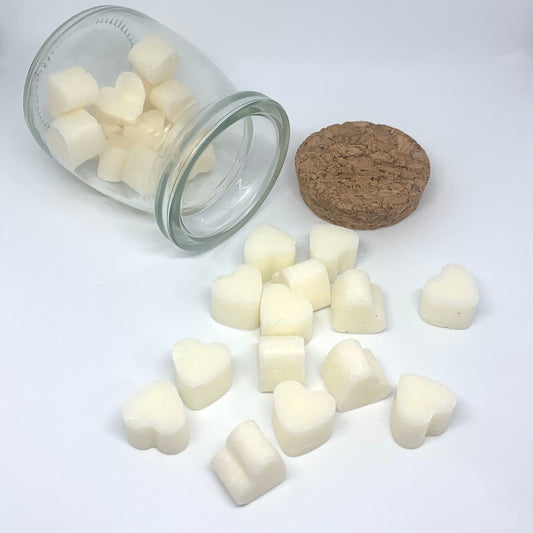 Small jar of heart-shapped wax melts with cork lid, spilling onto table.